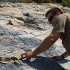 Un vecino de la zona muestra dos de los escasos fósiles que han sobrevivido al destrozo, ya rotos.