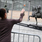 Una mujer prueba su puntería con la estatua de Franco.