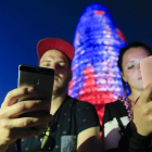 Dos personas utilizando su teléfono móvil frente a la Torre Agbar