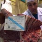 Un carnicero muestra el certificado de calidad de la carne gallega que vende en su local