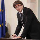 El president Carles Puigdemont en el momento de firmar la declaración, tras el pleno.