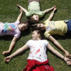 Cuatro niñas disfrutan del sol en el cesped de La Candamia.