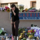 Una mujer, entre las flores y velas que se acumulan en el lugar del ataque a Giffords.
