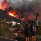 Unos caminantes observan y hacen fotos a la lava que sale del volcán. MIGUEL CALERO