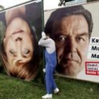 Dos hombres retiran carteles electorales de Merkel y Schröder