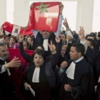 Abogados marroquíes agitan banderas contra los saharauis ante el tribunal.