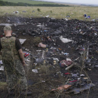 Un rebelde prorruso observa varios cadáveres junto a los restos del Boeing 777.