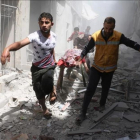 Dos hombres evacúan a una persona víctima de los bombardeos de hoy en el barrio de Al Qatarji de Alepo.