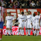Los jugadores del Madrid celebran la victoria ante la desazón de los atléticos.
