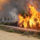 Un miembro de una cuadrilla forestal ataca a las llamas con una manguera.