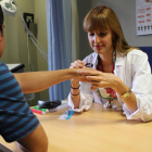 Elia Sarmaniego analiza una mancha en la mano de uno de sus pacientes.
