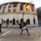 Dos manifestantes lanzan piedras al Ejército mientras arden dependencias del Parlamento.