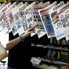 Una mujer mira con curiosidad y cierto temor la oferta informativa de la prensa griega.