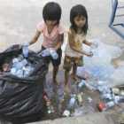 Unas niñas camboyanas recogen botellas y latas reciclables.