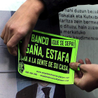 Un joven pone una pegatina en el cristal de un banco.