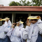 Un grupo de estudiantes prueban unos filtros para observar el eclipse de sol, este lunes en la isla indonesia de Ternate.