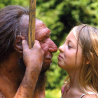 Una niña se acerca a una figura que representa un hombre de Neandertal.