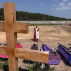 Un cura ortodoxo bendice féretros en la fosas abiertas en el cementerio de Bucha. ROMAN PILIPEY