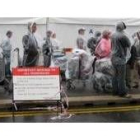 Los pasajeros hacen cola bajo la lluvia a las puertas del aeropuerto londinense de Heathrow