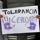 Un manifestante sostiene una pancarta que exige tolerancia cero.
