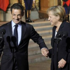 Sarkozy y Merkel sonríen y se dan la mano.