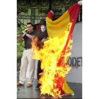 Un encapuchado quema una bandera española ante la mirada de Otegi