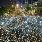 Manifestantes estudiantiles sostienen sus teléfonos  en una muestra de solidaridad durante las protestas frente a la sede del Consejo Legislativo de Hong Kong.