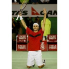 Federer, de rodillas, levanta los brazos tras ganar la final de Australia