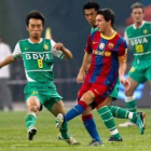 Lionel Messi (derecha), controla el balón ante el jugador del Beijing Guo, Yang Hao.