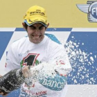 Simón, exultante en el podio, destapa el champán por su título mundial.