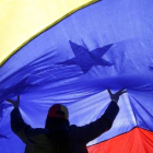 Una mujer sujeta una gran bandera de Venezuela.