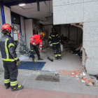 Los bomberos retiran los cascotes y asegura el local con el coche ya fuera del mismo. L. DE LA MATA