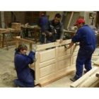 Alumnos de la escuela taller de Bembibre, del área de carpintería, ensamblando una puerta.