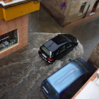 Un coche circula por una céntrica calle de Valencia de Don Juan anegada por la tormenta