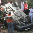 Los bomberos y los médicos atendiendo al herido en el coche.
