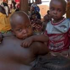 Un niño nigeriano víctima de la malnutrición, tumbado sobre su madre, espera ayuda en Maradi