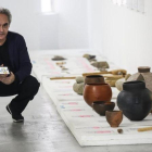 Ferran Adrià sostiene un móvil con la 'app' Tu cuento en la cocina, junto a objetos de cocina del Neolítico, en el BulliLab.