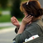 Una mujer habla a través de su teléfono móvil sentada en el banco de un parque