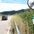 La maleza ocupa parte de la calzada de la carretera y cubre las señales.
