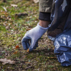 Proyecto Libera. Un voluntario recoge colillas en el campo.