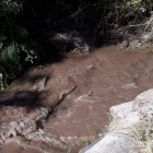 El agua del reguero discurría turbia como el barro. CAMPOS