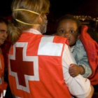 Un niño es recogido de una patera por un miembro de Cruz Roja Española