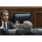 Zapatero conversa con el diputado de IU Gaspar Llamazares, de espaldas, en el pleno del Congreso.