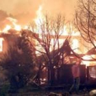 Un hombre intenta ayer, en vano, salvar su casa mientras ésta es pasto de las llamas