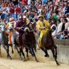 Varios competidores se disputan el Palio durante la carrera.