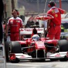 Alonso parado con su Ferrari en los boxes.