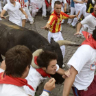 Uno de los Miura embiste a un mozo durante el transcurso del encierro.