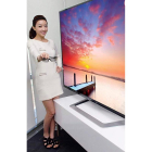 Una modelo posa junto a un televisor de alta definición y 3D.