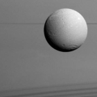 Panorámica de Dione con los anillos de Saturno al fondo.
