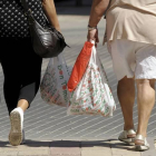 Dos mujeres llevan bolsas de plástico de la compra